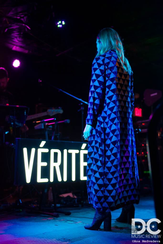VÉRITÉ standing with her back to the audience